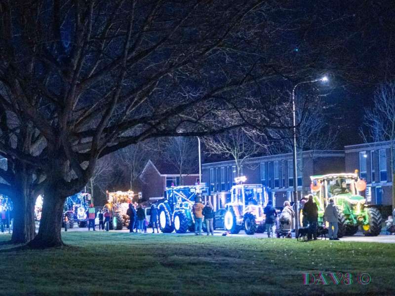 Een rij met tractoren volop aangekleed met lampjes