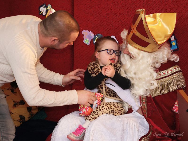 Sinterklaas met een meisje op schoot en haar begeleider