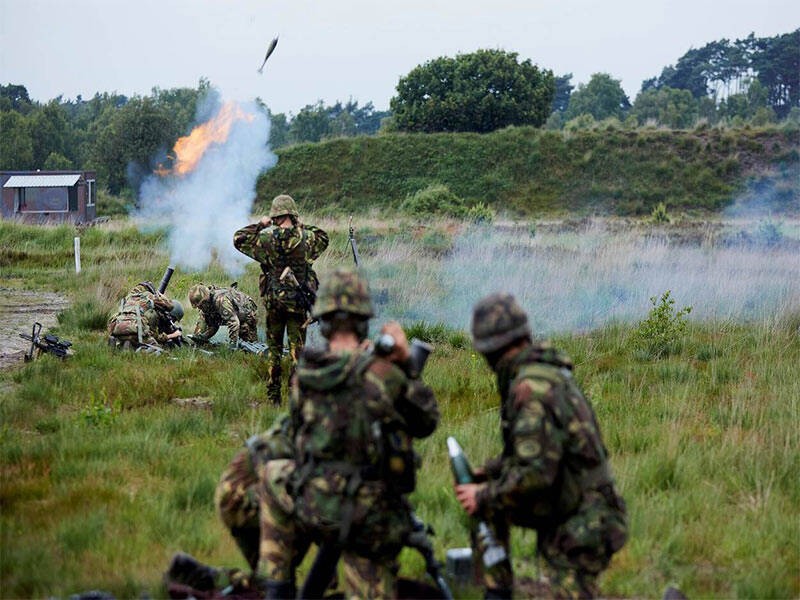 militairen die in het veld aan de slag zijn met het afschieten van mortieren